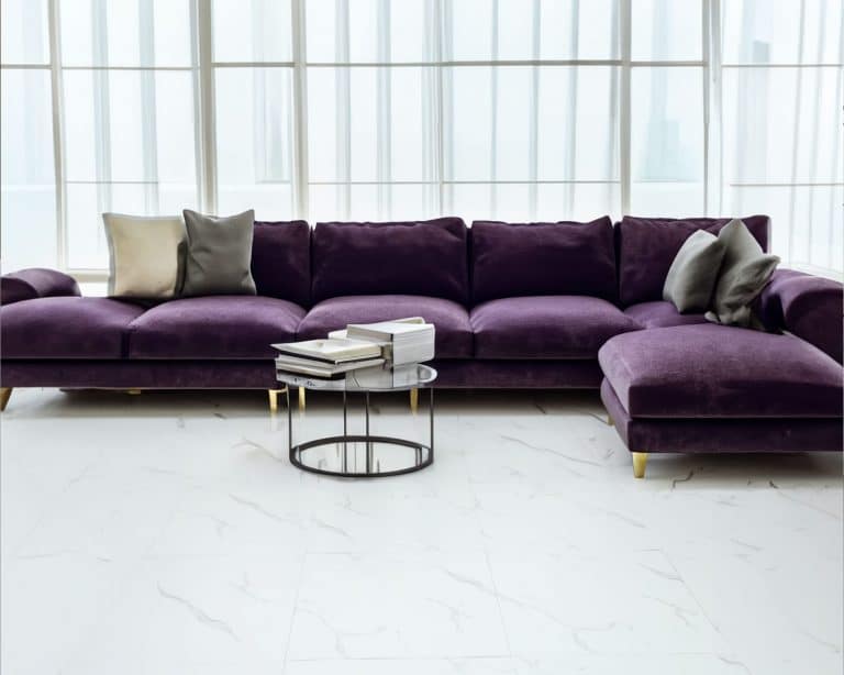 Cozy purple velvet sofa by big windows