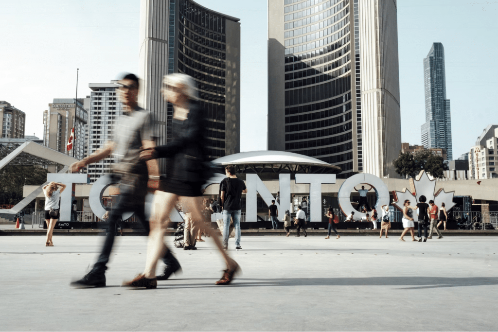 people walking around the toronto sign